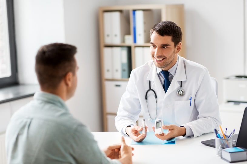 A kind doctor talks to a patient in a light office.