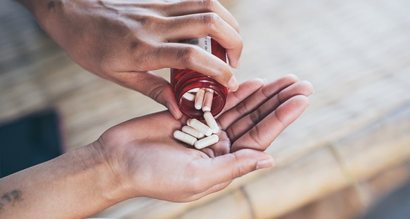 Woman pouring pills put of the bottle.