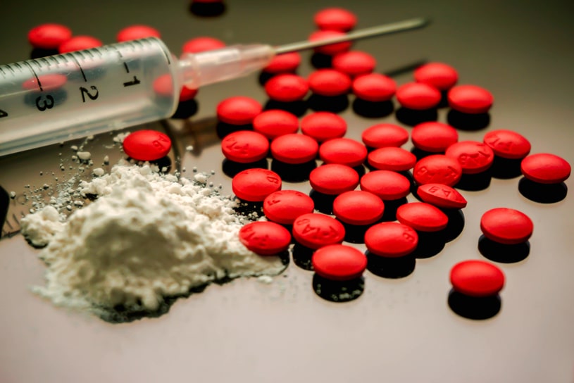 There are red tablets, syringes and powder on the table.