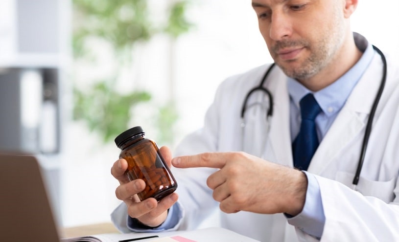 Doctor pointing at tablets in the bottle.