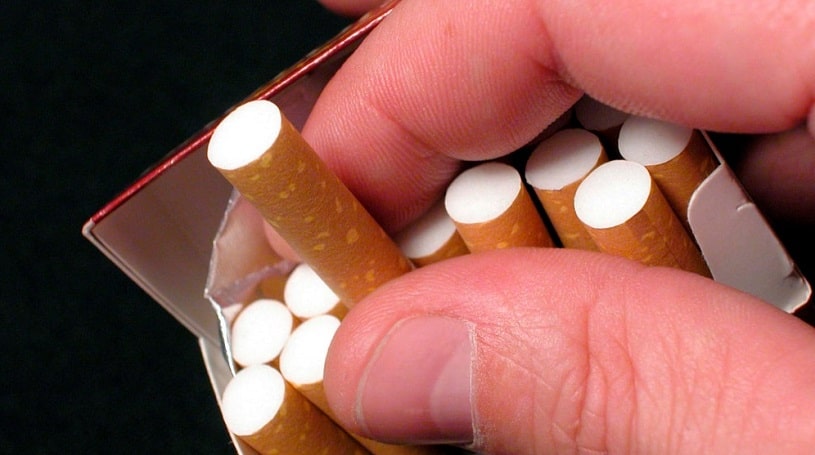 Hand pulling a cigarette out of the pack.