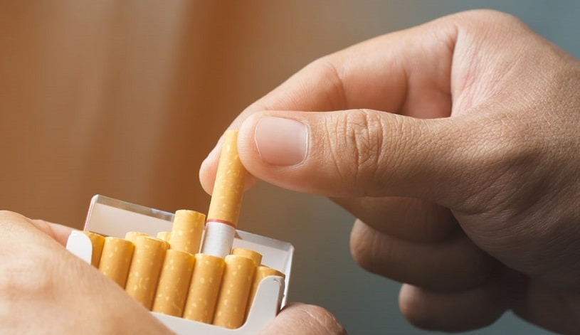 Hand pulling out a cigarette.