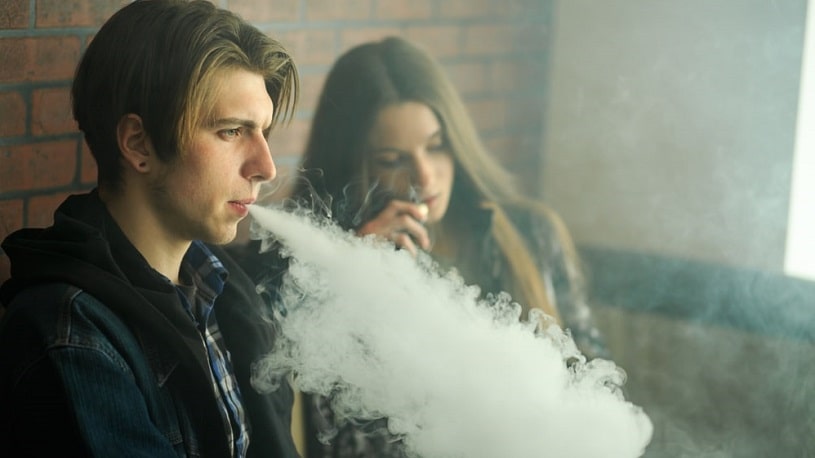 Young man vaping next to a girl.