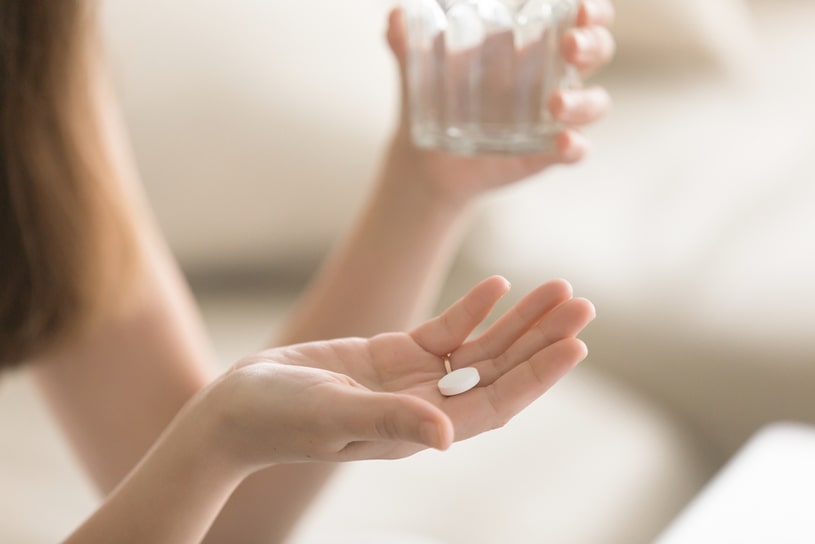 The girl takes an Ambien pill in a light room.