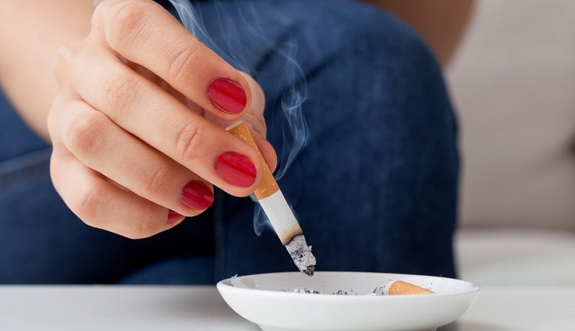 Woman smoking and using ashtray.