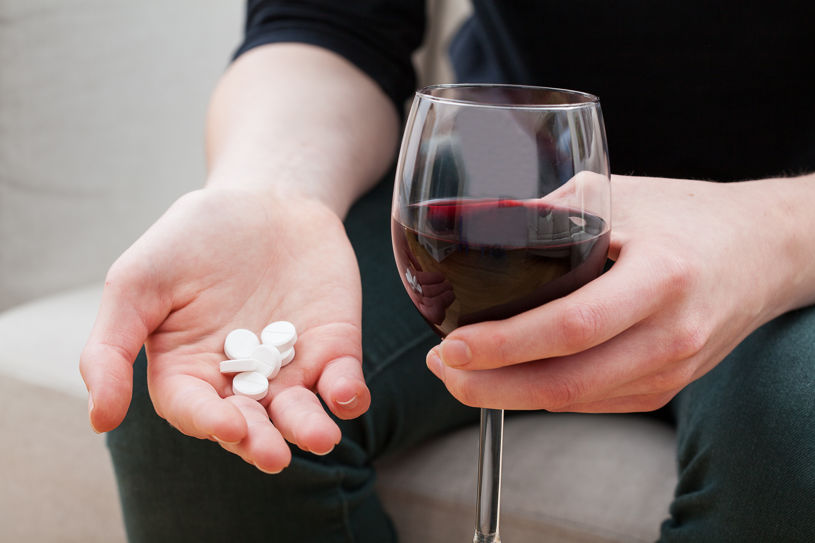 A man is holding pills and alcohol.