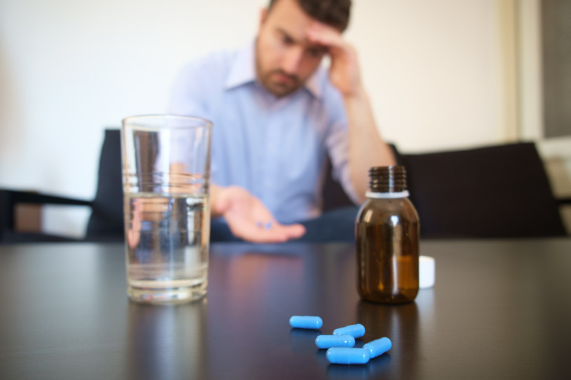 A man sitting with Flexeril pills in his hand.