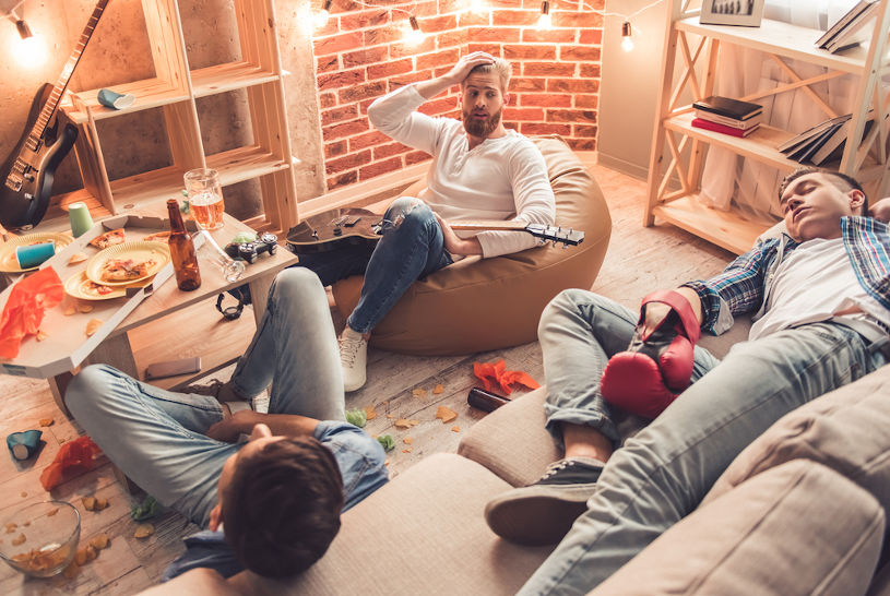 Guys are sleeping in messy room after having a party.