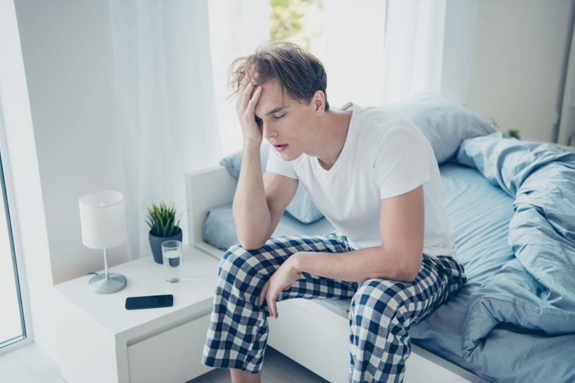 Exhausted unhappy man experiences hangover .