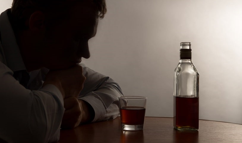 Man addicted to alcohol looking at the bottle.