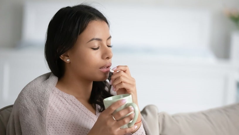 Woman holding a cup and Klonopin pill.