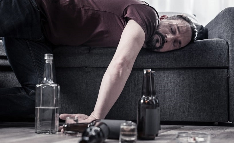 Drunk man with a lot of alcohol bottles.