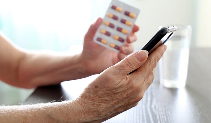 Man with smartphone and pills in hands reading about Valium duration.