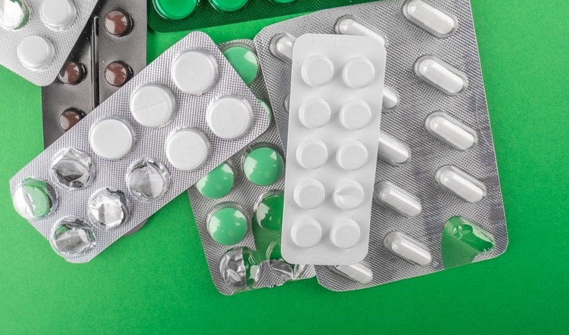 Different pills in blisters on green background.