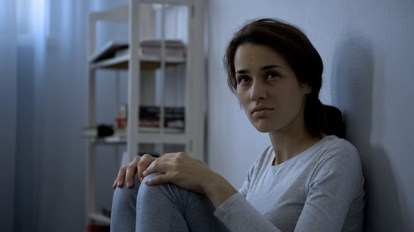 Depressed woman sitting on the floor in the dark room.
