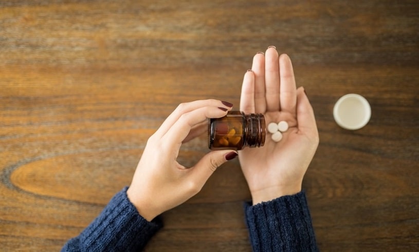 Female spilling Norco pills onto a hand.