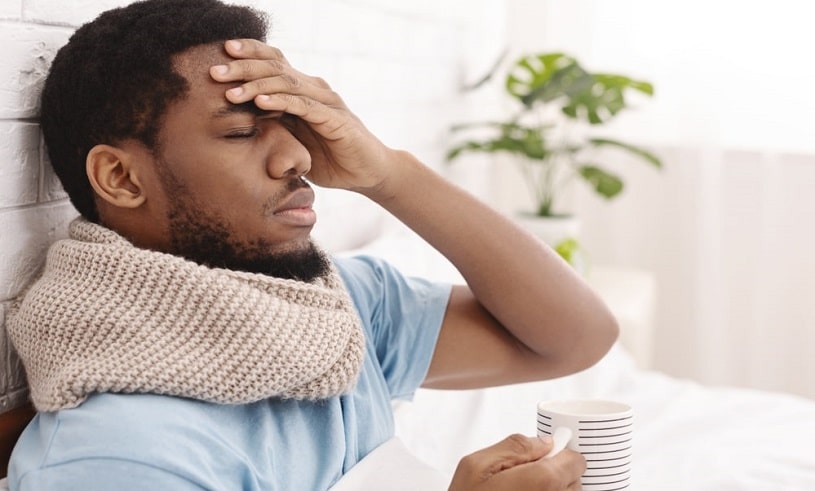 Sick man having a fever touching his head.