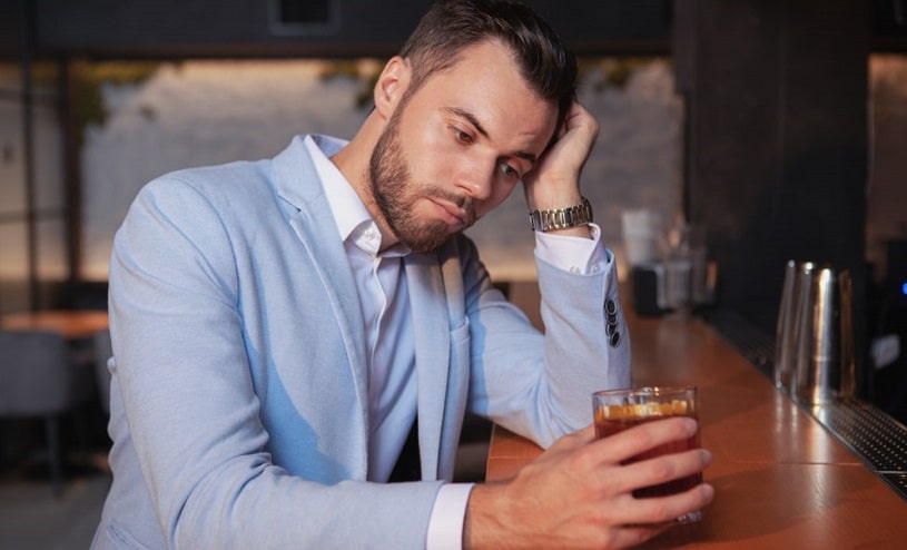 Depressed man drinking alone at a bar.