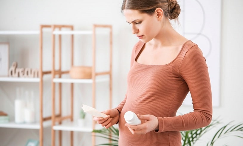 Pregnant woman reading Norco instruction at home.