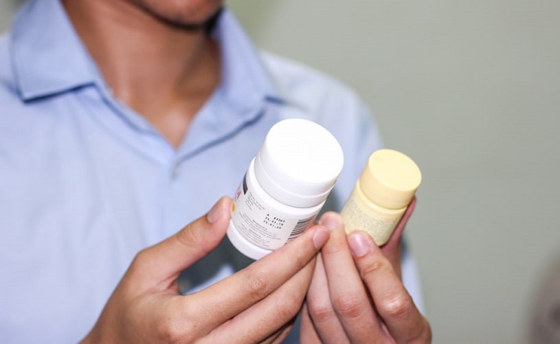 Man holding norco and ibuprofen bottles.