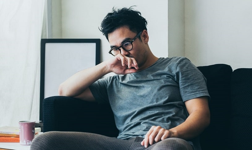 Sad serious depressed man sitting on the couch.