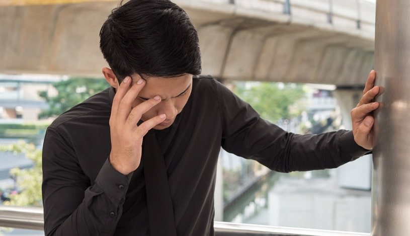Dizzy man experiences tramadol withdrawal symptoms and holds his head.