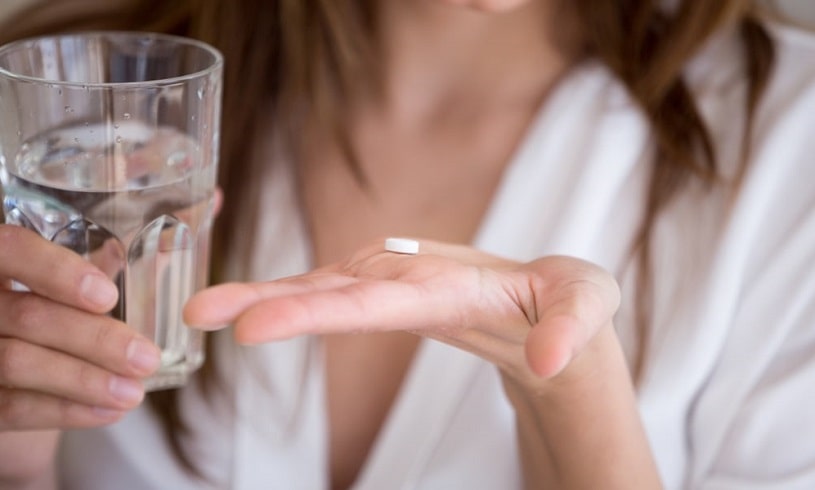 Woman holding a pull with a glass of water in hands.