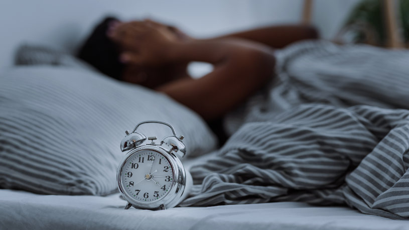 A man lying in bed experiences insomnia and can't fall asleep.
