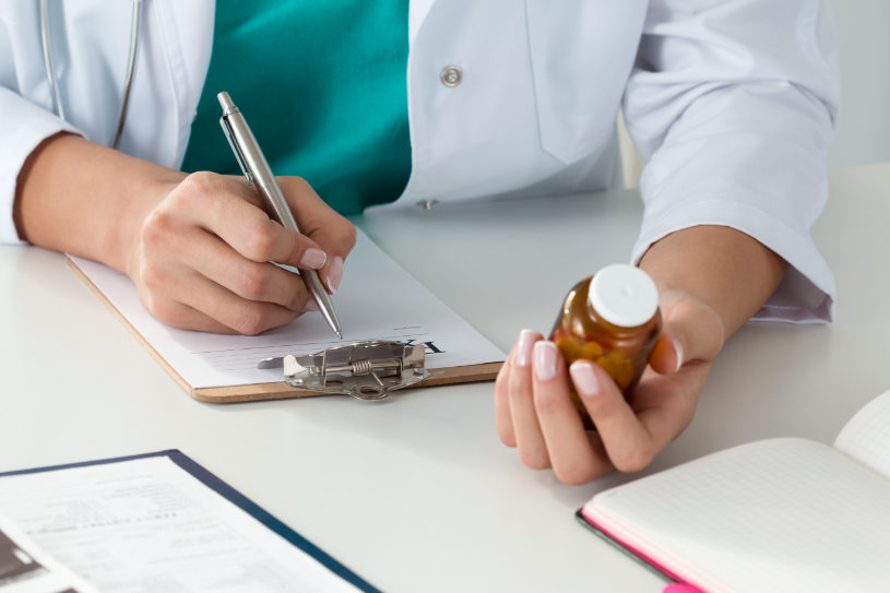 A medical worker holds Fiorinal pills and writes a prescription to a patient.