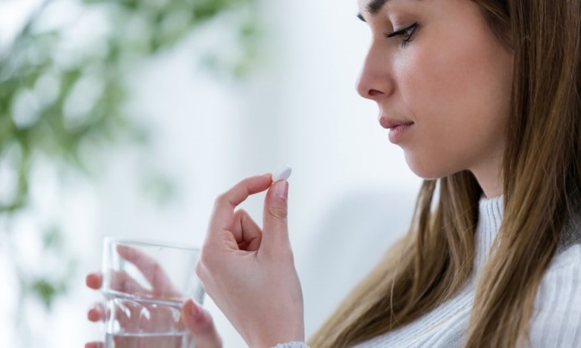 Woman holing a pill and worried about her Lortab abuse.