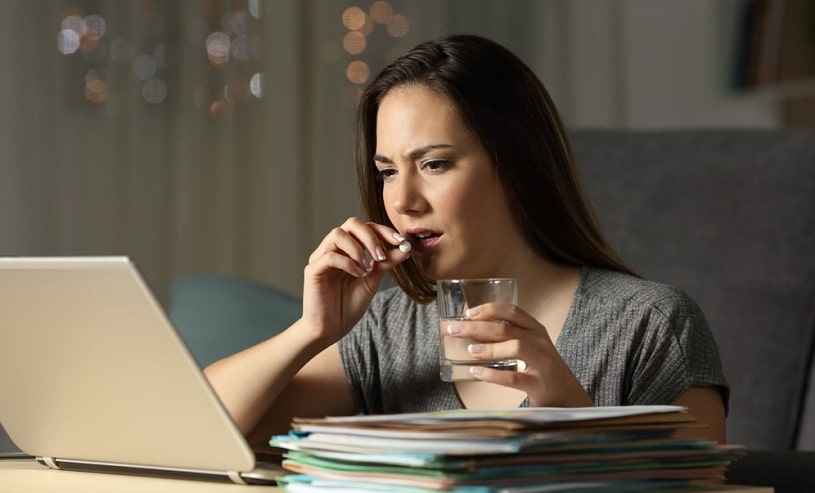 Stressed student taking dexedrine to study at night.