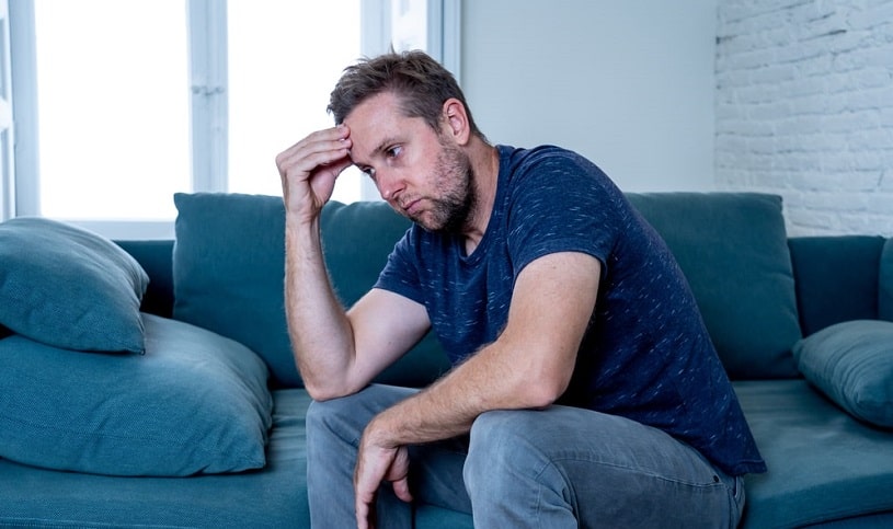 Unhappy depressed man sitting on the couch.