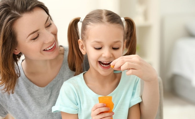 Mother giving a pill to a daughter.