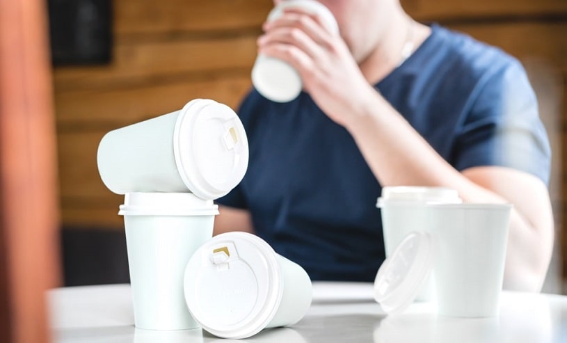 Man sitting at a table with many cups of coffee.