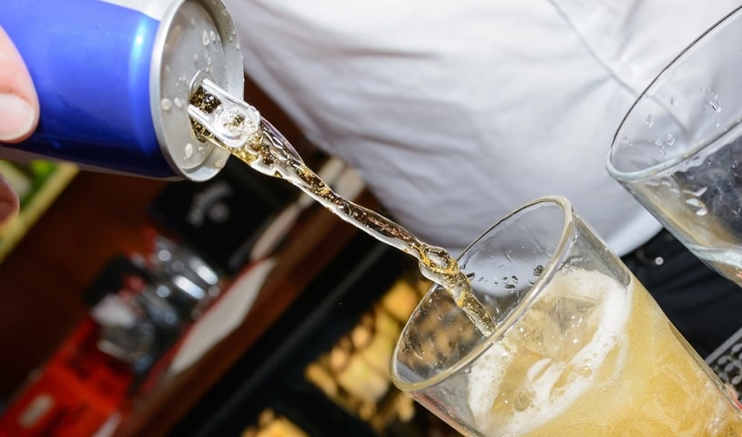 Energy drink being poured into a glass with alcohol.