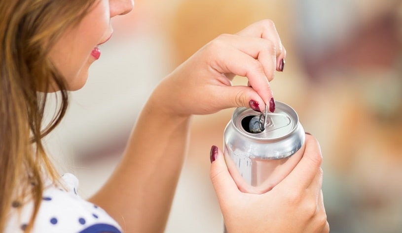 Girl opening a can of caffeinated drink.