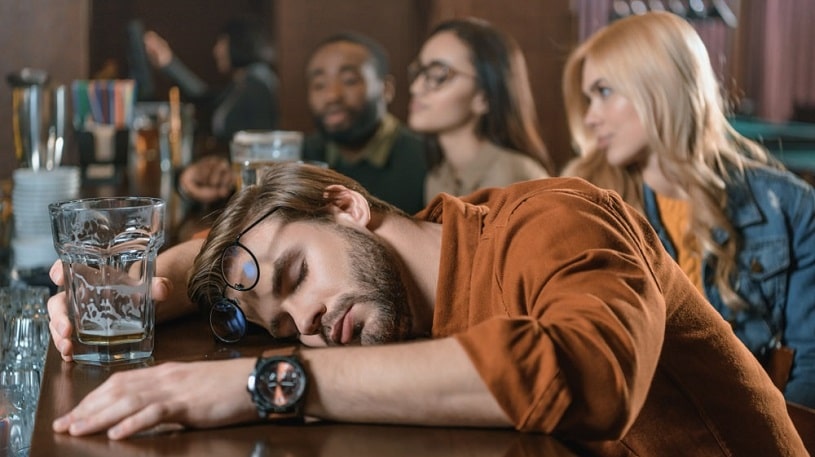 Drunk man sleeping at a bar.