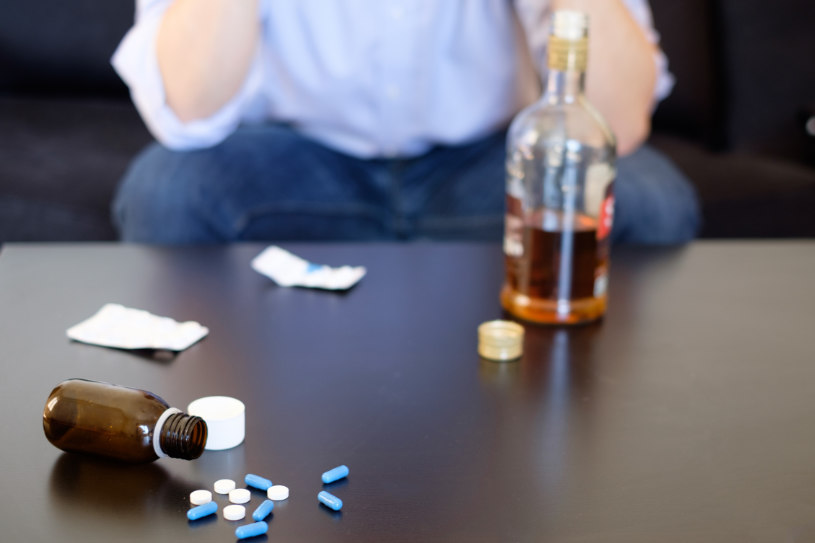 A bottle of alcohol and Amitriptyline pills are on the table.