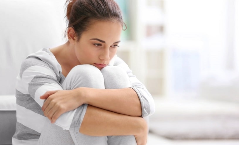 Depressed sad woman sitting on the couch.