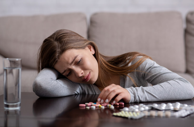 Depressed woman sit on the groud and watches on pills.