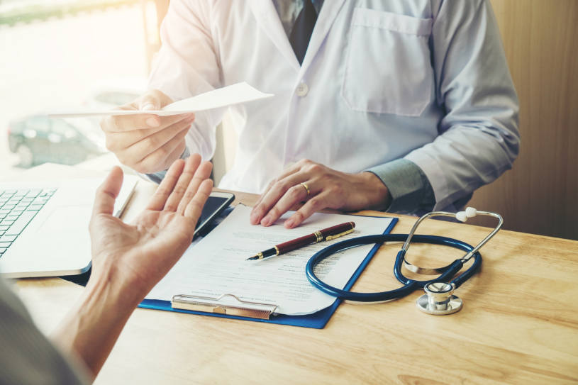 A doctor gives prescription to a patient.