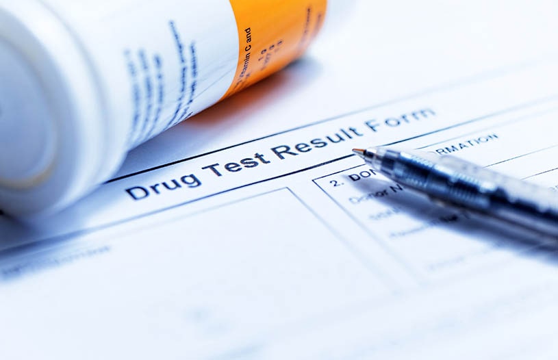A paper with an imprint drug test and a pen.