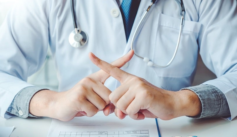 Doctor saying no to patient, forbidding something and crossing fingers.