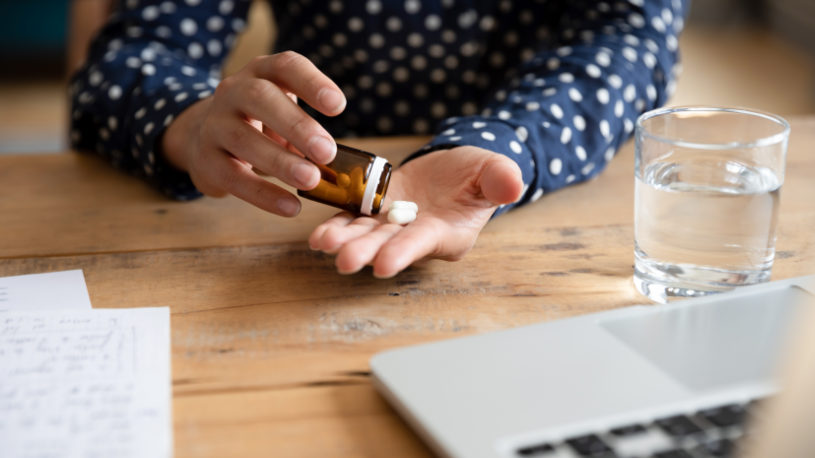 Close up young woman taking out pills from bottle.