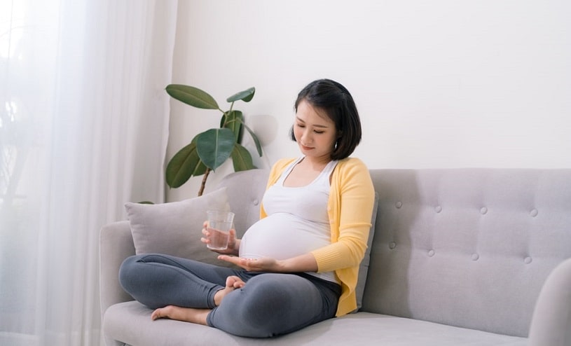 Pregnant woman on the couch thinking about taking Fioricet.