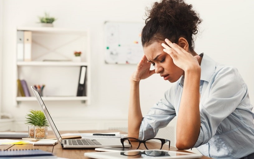 Woman has a headache at the office near laptop.
