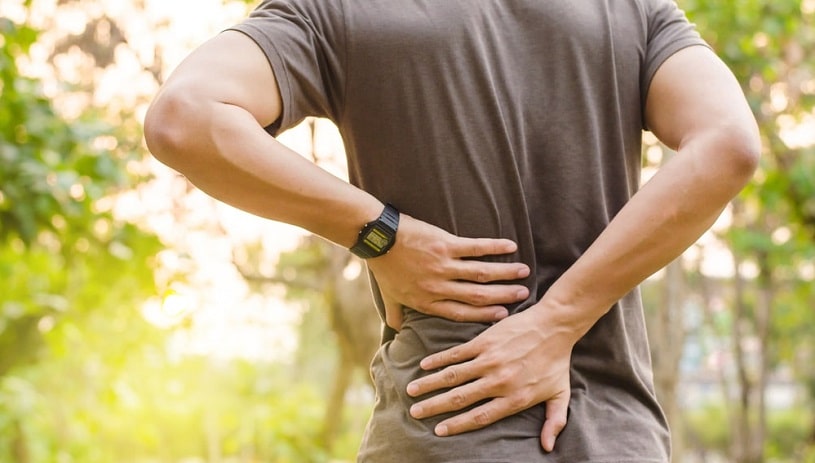 Man experiencing back pain outside.