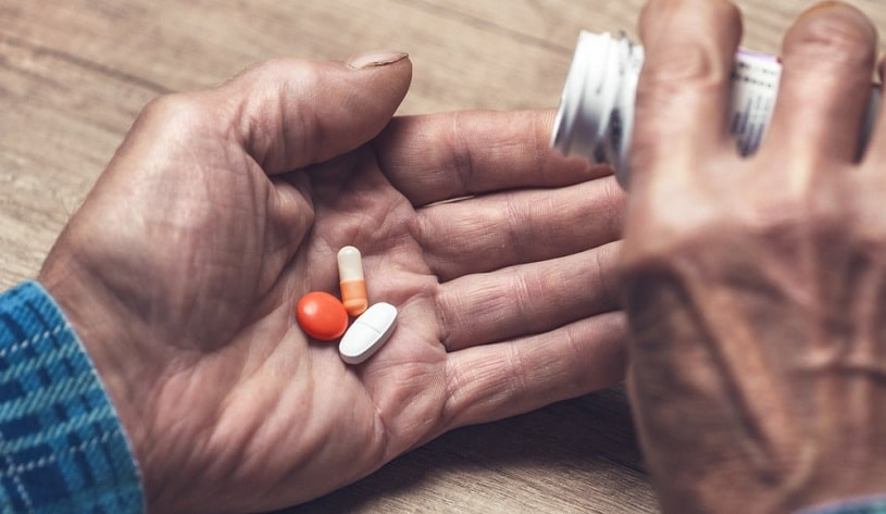 Senior pouring Meloxicam pills into a hand.