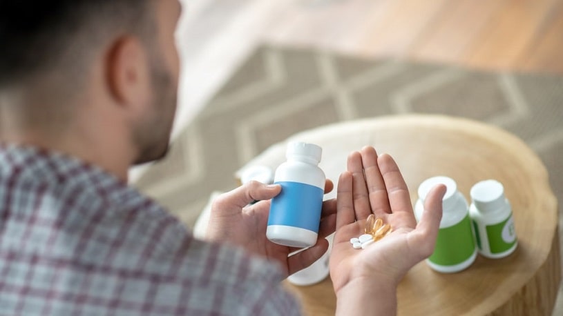 Man holding soma bottle and pills in hand.