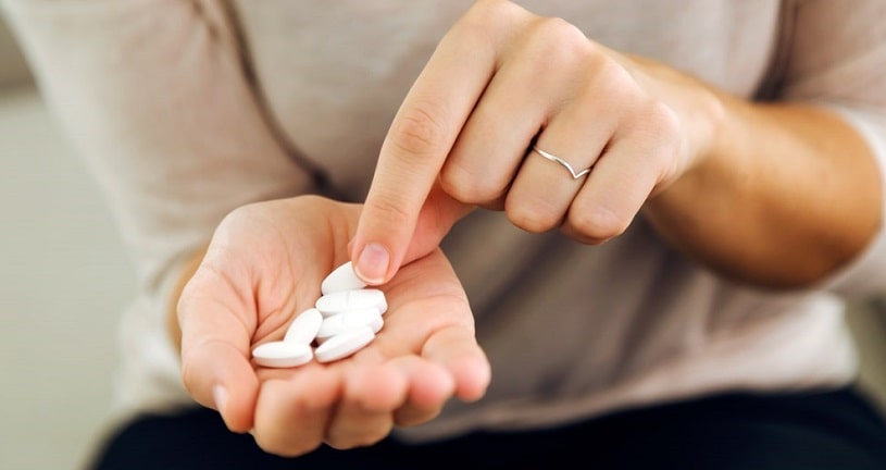 Woman holding pills in her hand, counting them.